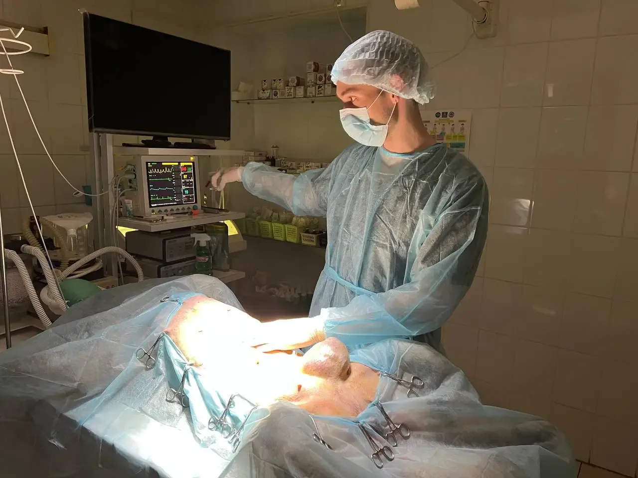 Surgeon operating on a draped patient under the theatre lamp